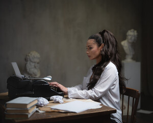 A female writer works at a typewriter, writing an essay.