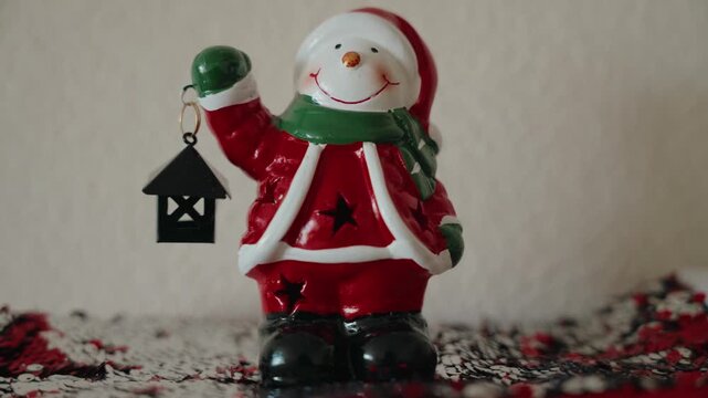 A Santa-style snowman toy holds a lamp
