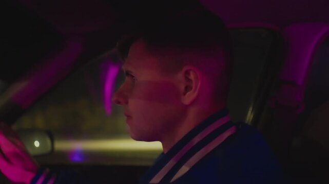 white driver steering neon night motion determined expression earbuds visible firm grip on wheel streetlight streaks dashboard glow dynamic urban drive focused navigation tense energy