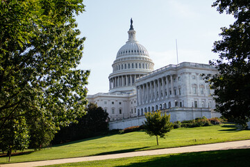 United States Capitol building with iconic dome and American flag under clear blue sky in Washington DC, USA. g.
