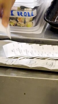 Chef Sorting Order Dockets in Busy Japanese Kitchen