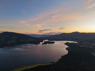 Obraz premium Vista aérea de la Represa del Neusa, Cundinamarca, con bosque y reflejos en el agua al atardecer.