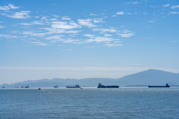 Fototapeta premium Cargo Ships on Calm Ocean Under Clear Sky