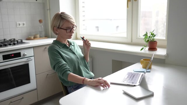 Middle aged business woman freelancer working on laptop, reading documents, nervously tapping fingers and clicking pen. Female with ADHD and nervous expression, anxiety and hyperactivity problems.