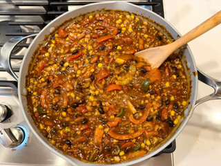 Top view of homemade organic chili in pan on top of stove being cooked