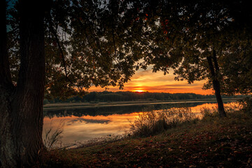 Beautiful summer sunset and colorful sky over the lake. Clouds are reflected in the calm water. Beauty in this world
