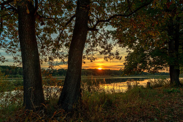 Beautiful summer sunset and colorful sky over the lake. Clouds are reflected in the calm water. Beauty in this world