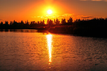 Beautiful summer sunset and colorful sky over the lake. Clouds are reflected in the calm water. Beauty in this world