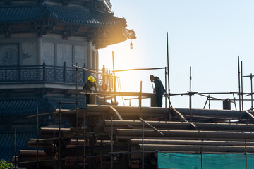 Fototapeta premium Construction Workers on Scaffolding Near Historic Building