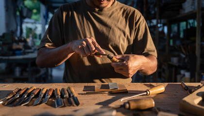 Person sharpening a chisel in a woodworking workshop with various tools.