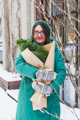 A girl holds a bouquet with coniferous branches