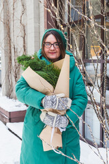 A girl holds a bouquet with coniferous branches