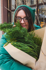 A girl holds a bouquet with coniferous branches