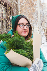 A girl holds a bouquet with coniferous branches