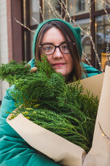 A girl holds a bouquet with coniferous branches