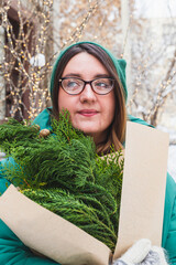 A girl holds a bouquet with coniferous branches