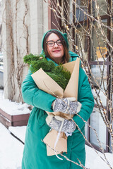 A girl holds a bouquet with coniferous branches