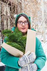 A girl holds a bouquet with coniferous branches
