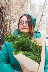 A girl holds a bouquet with coniferous branches
