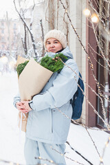 A girl holds a bouquet with coniferous branches
