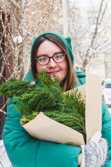 A girl holds a bouquet with coniferous branches