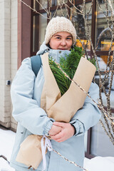 A girl holds a bouquet with coniferous branches