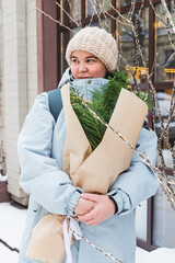 A girl holds a bouquet with coniferous branches