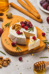 Brie cheese on a board with walnuts, honey and berries