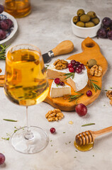 Brie cheese on a board with walnuts, honey and berries