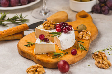 Brie cheese on a board with walnuts, honey and berries