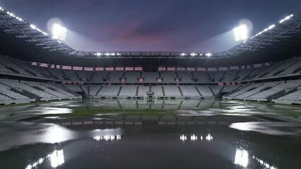 Empty stadium with wet field and bright lights at dusk