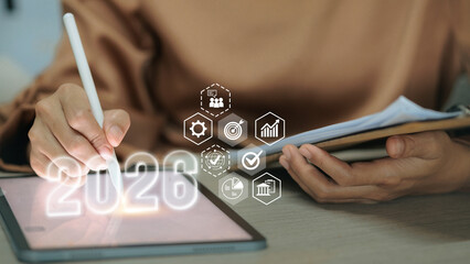 Business woman writing on tablet with 2026 number and hexagonal business strategy icons.