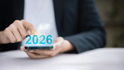 Person holding smartphone with 2026 number and digital fireworks celebration.