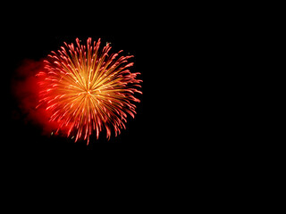 Fototapeta premium Fiery red and golden fireworks overlay blooming on black background, intense glowing sphere with smoky plume drifting left, dramatic warm pyrotechnic burst ideal for powerful festive celebration artwo