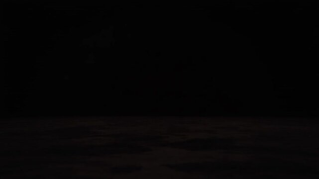 Extremely dark, almost black image with a barely visible textured surface at the bottom, suggesting a void or deep shadow.