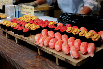 Many pieces of sushi made from salmon and unagi on the wooden tray for selling
