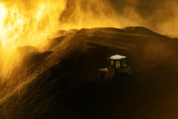 View from above. A coal pile at dawn. A bulldozer is laying coal.
