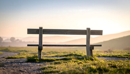 Wooden bench on grassy hill at sunrise.