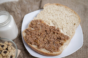 Bread with minced beef and union on a table. With white milk and snack for breakfast