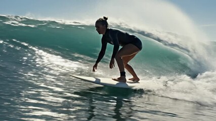 Female surfer riding a large ocean wave with skill and balance, enjoying the thrill of the sport.