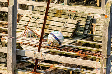 Old fishing floats on chaotic wooden dock with rusted chain and anchor room for text suitable as background shot in Nova Scotia Canada in summer