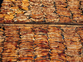Dried fish laid out in organized rows on wooden racks, showcasing textures and colors. Ideal for commercial use in food industry and culinary themes.