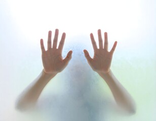 Two human hands pressed against frosted glass reaching forward expressing separation longing hope and emotional connection through blurred barrier
