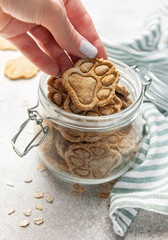 Woman hand taking homemade paw print dog treats from jar