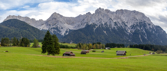 Scenic panoramic landscape of wide open meadow with small barns and mountains at Garmisch-Partenkirchen in Germany © SNEHIT PHOTO