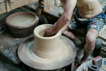 Selective focus on the clay work on the spinning tray with hands of worker