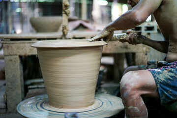 Selective focus on the clay work on the spinning tray with hands of worker