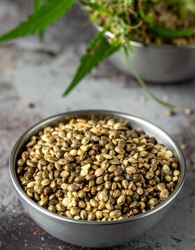 Close-up of hemp seeds in bowl, with leaves in background