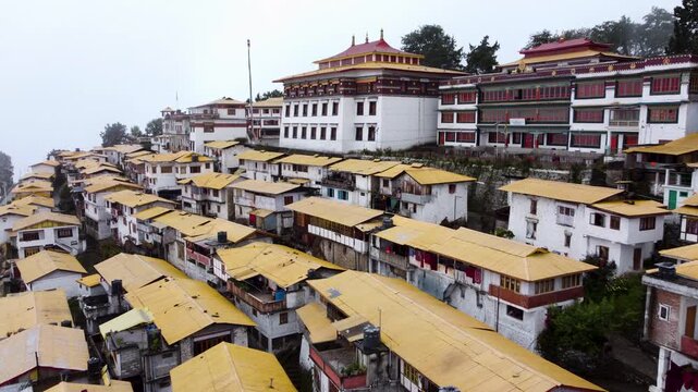 Aerial drone view of monastery buildings and yellow roof houses in Tawang town