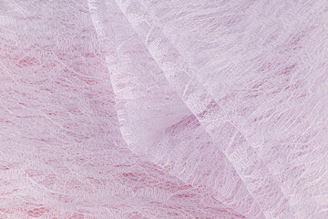 White lightweight guipure fabric neatly folded on a pink background. delicate soft folds of floral pattern. Product presentation. Layout